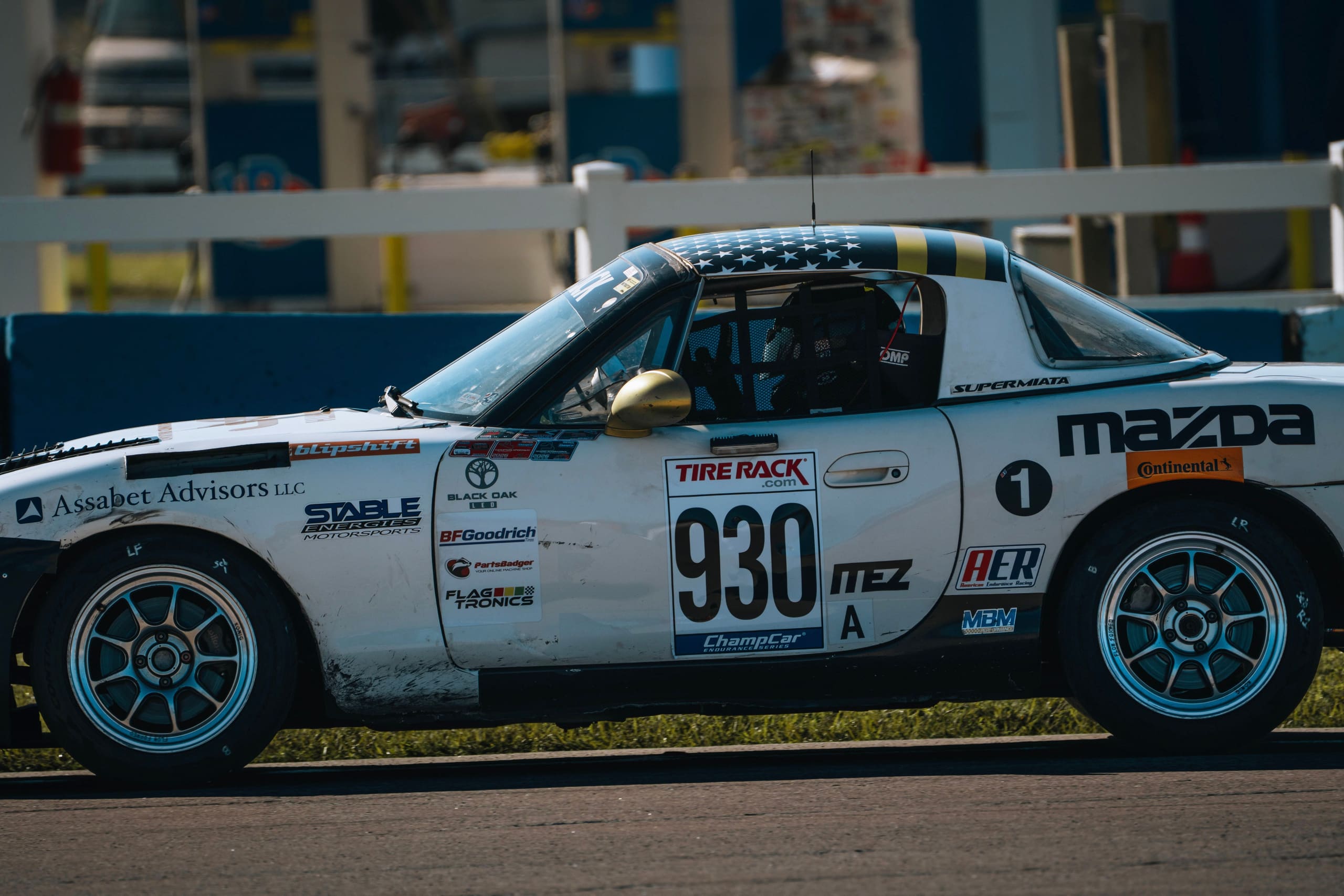 Side elevation of the #930 Mazda MX-5 in the Sebring pit lane, showing the full livery.