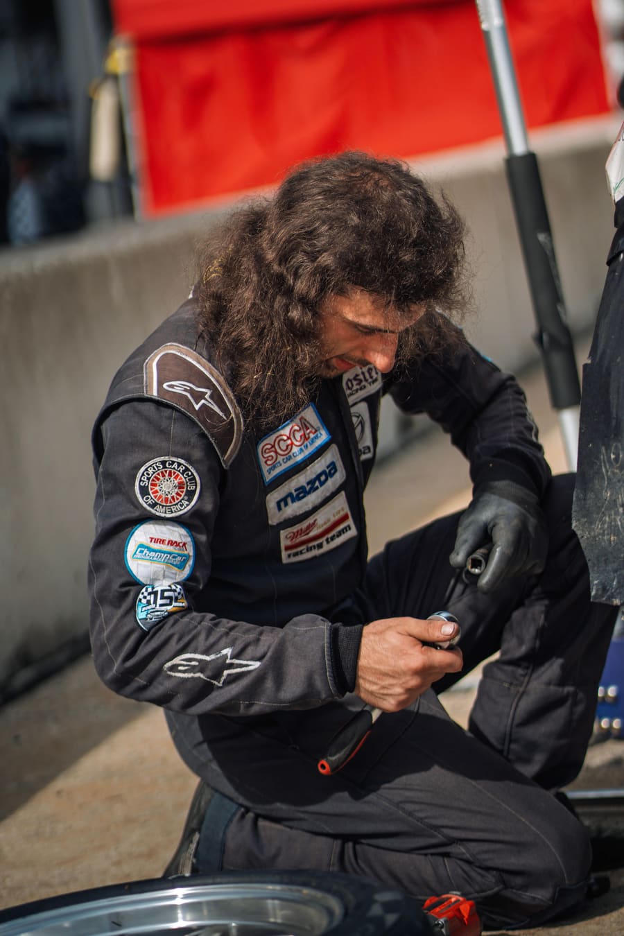 A mechanic working on a wheel in the paddock.
