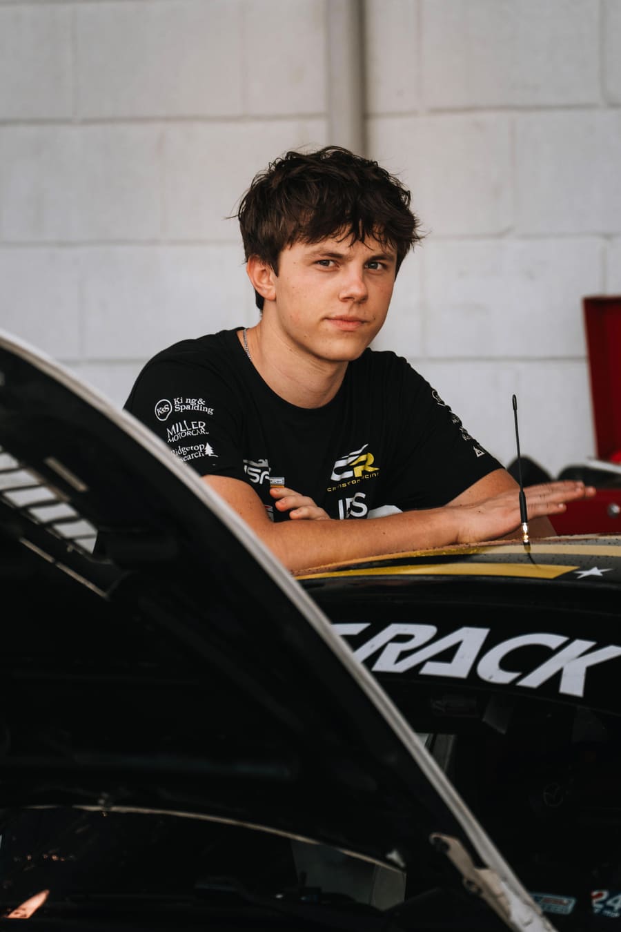 The youngest member of the team leaning on the car.