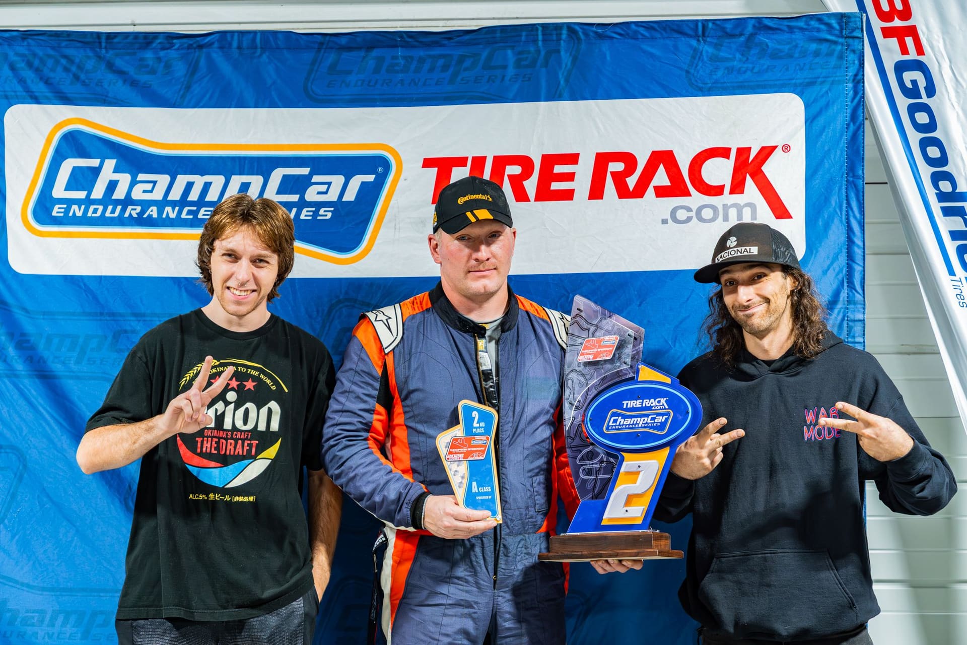 Three of the team on the ChampCar podium holding the second-place trophy.