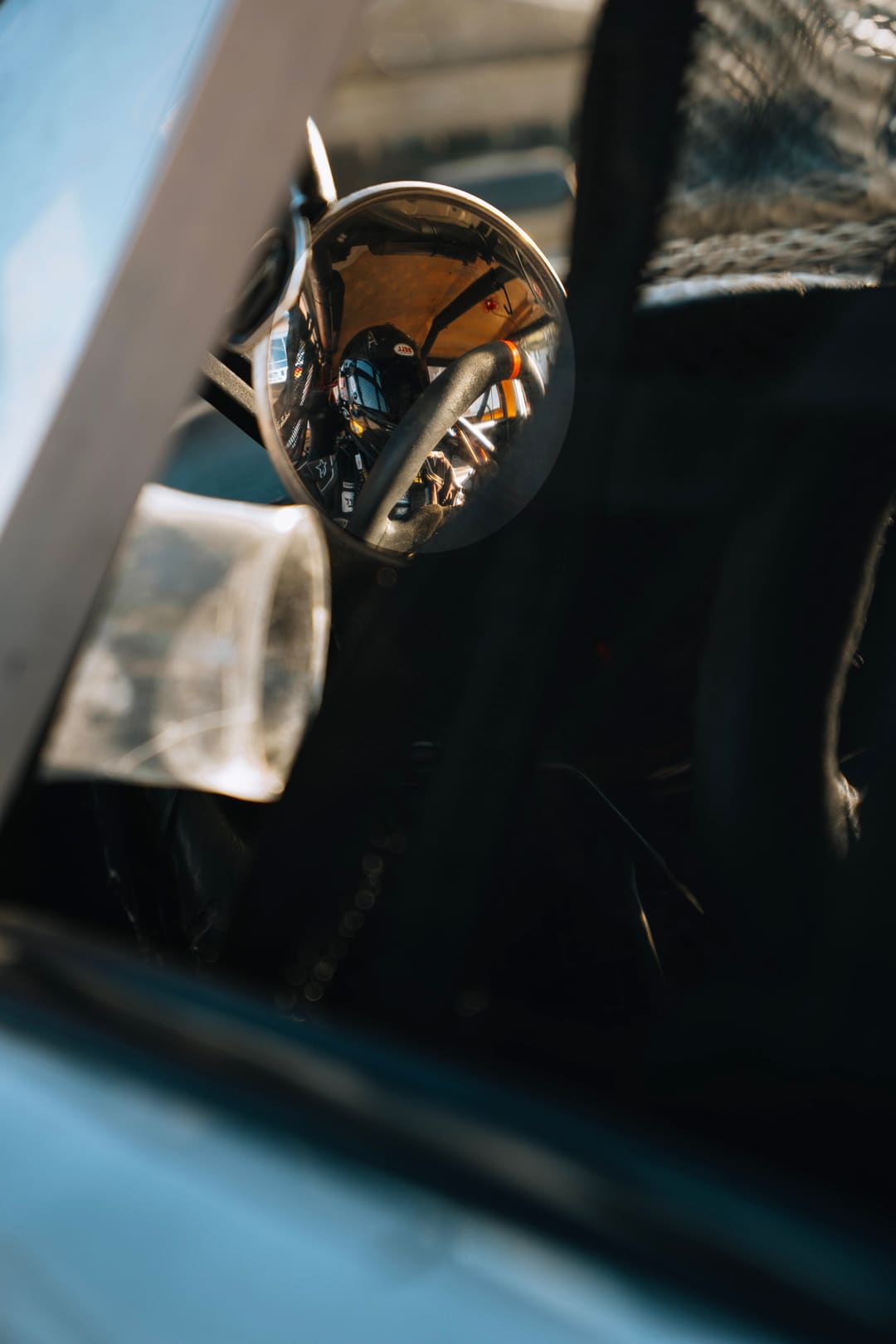 A driver reflected in the car mirror before a session.
